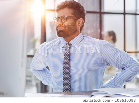 Guy Having Backache Massaging Aching Lower Back Suffering From Pain Sitting At Workplace In Modern Office Guy Having Backache Massaging Aching Lower Back Suffering From Pain Sitting At Workplace In Modern Office 109636398