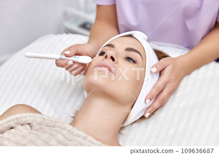 female hand touching the patient's face with a brush. beautician applies the mask to female face. facial skin care. female hand touching the patient's face with a brush. beautician applies the mask to female face. facial skin care. 109636687