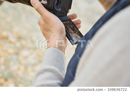Professional wedding photographer holding camera against bride and groom Professional wedding photographer holding camera against bride and groom 109636722