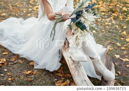 bride wearing white boots holding beautiful autumn bouquet. copy space bride wearing white boots holding beautiful autumn bouquet. copy space 109636723