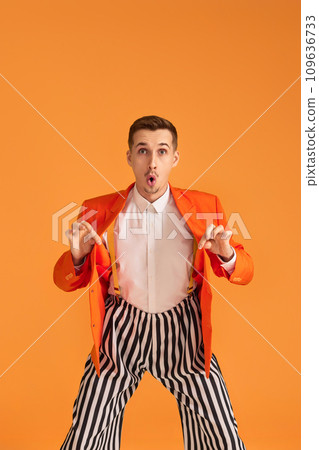 crazy funny young man in orange jacket and striped pants on yellow background. 109636733