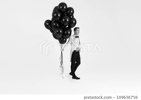 elegant caucasian man in white suit tuxedo with black air balloons on white background. Full size elegant caucasian man in white suit tuxedo with black air balloons on white background. Full size 109636756