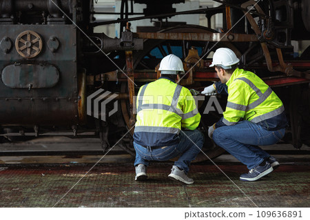 Engineer team service maintenance old broken diesel steam train park at railway depot team working with safety suit. Engineer team service maintenance old broken diesel steam train park at railway depot team working with safety suit. 109636891