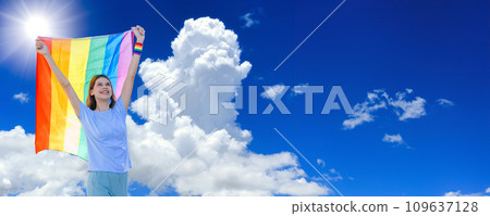 LGBTQ woman with rainbow flag on summer blue sky for Transgender freedom pride month advertising wide banner 109637128