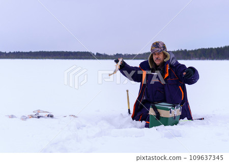Man Holding a Fish in the Snow. Winter fishing, adventure. Banner, copy space 109637345