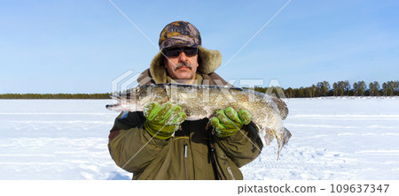 Man Holding a Fish in the Snow. Winter fishing, adventure. Banner, copy space 109637347