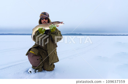 Man Holding a Fish in Hands. Winter fishing. Banner, copy space 109637359