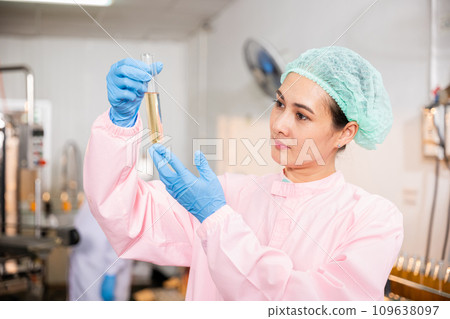 A woman food engineer in juice beverage factory executes food and beverage quality and safety testing employing test tubes to sample basil or chia seeds in bottled products in laboratory control. A woman food engineer in juice beverage factory executes food and beverage quality and safety testing employing test tubes to sample basil or chia seeds in bottled products in laboratory control. 109638097