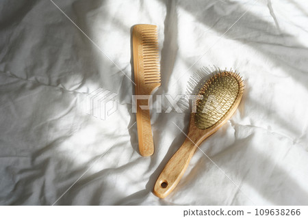 Wooden hairbrushes on white bed background with shadows from window Wooden hairbrushes on white bed background with shadows from window 109638266