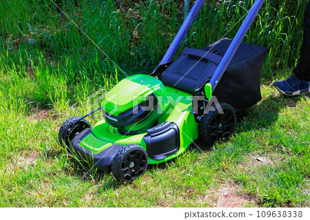 Mowing green grass using an electric lawn mower is gardener man 109638338