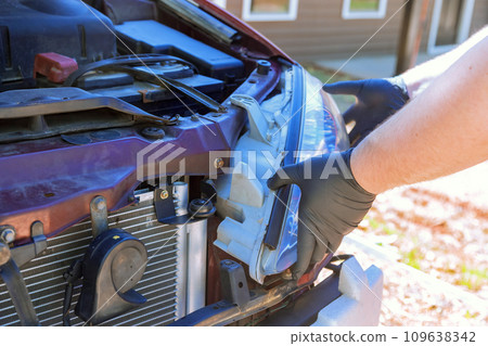 During service car repair, repairman assembles an automobile headlight During service car repair, repairman assembles an automobile headlight 109638342