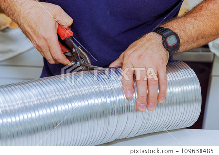 Man used scissors to cutting flexible aluminum corrugated pipe for vent air duct Man used scissors to cutting flexible aluminum corrugated pipe for vent air duct 109638485