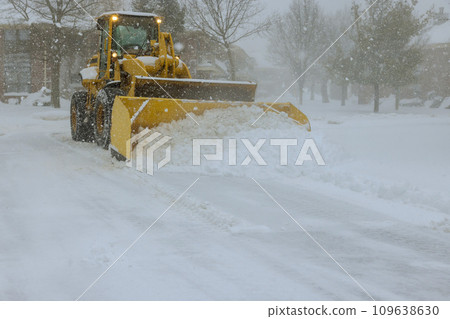 In midst of heavy snowstorm, snowplow truck removes snow from car parking lot 109638630