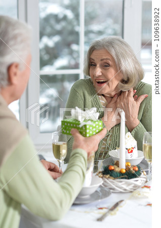Elderly couple at the dinner table giving a New Year's gift Elderly couple at the dinner table giving a New Year's gift 109638922