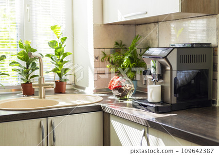 Modern electric coffee machine with cup on countertop in kitchen Modern electric coffee machine with cup on countertop in kitchen 109642387