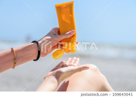 A woman holding bottles of sunscreen in her hands. 109643041