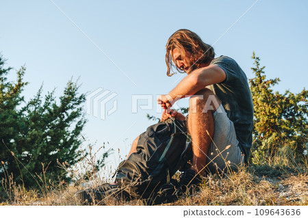 Man hiker sitting on rock resting during trekking in the countryside 109643636