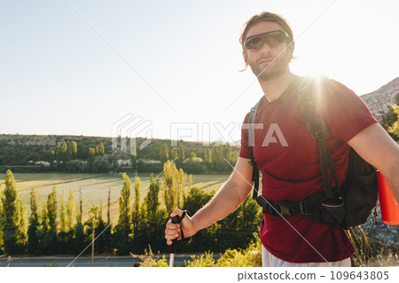 Young man hiker travels through the mountains with trekking poles for nordic walking 109643805