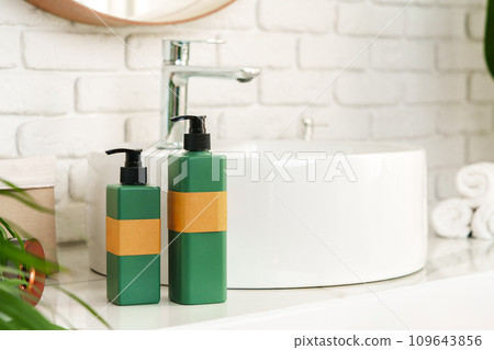 Soap and cream dispenser jars near the sink in a bathroom Soap and cream dispenser jars near the sink in a bathroom 109643856