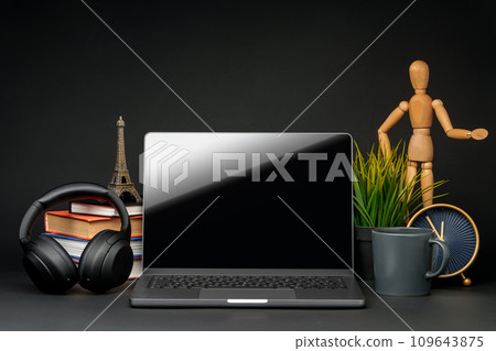 Open laptop with wooden mannequin on table against black background Open laptop with wooden mannequin on table against black background 109643875