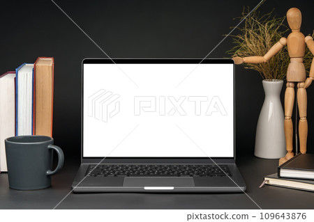 Open laptop with wooden mannequin on table against black background 109643876