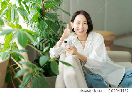 Middle-aged woman operating a smartphone on the sofa 109645482