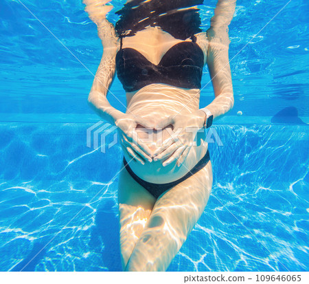 Pregnant bliss unfolds underwater as a woman forms a heart with her hands a serene and joyful aquatic moment celebrating life and love Pregnant bliss unfolds underwater as a woman forms a heart with her hands a serene and joyful aquatic moment celebrating life and love 109646065