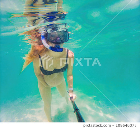 In an ethereal underwater scene, a pregnant woman gracefully floats, embodying the beauty of maternity beneath the tranquil surface of the sea In an ethereal underwater scene, a pregnant woman gracefully floats, embodying the beauty of maternity beneath the tranquil surface of the sea 109646075