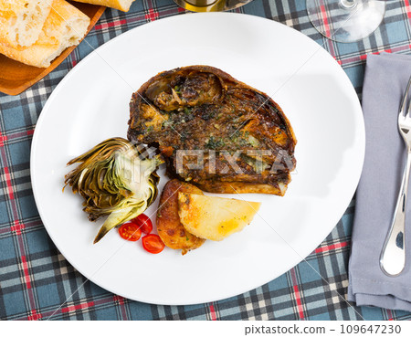 Cabeza de cordero - spanish dish. Lamb head with artichoke, tomatoes and potatoes 109647230