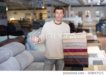 man offers to opt for furniture fabrics from their collection in shopping center 109647515