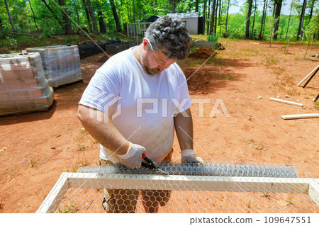 An employee is using scissors metal to cut metal mesh An employee is using scissors metal to cut metal mesh 109647551