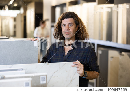Handsome man in hardware store choosing floor ceramic tiles for his apartment 109647569