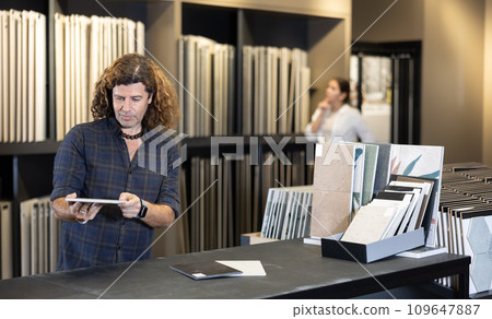 Focused man choosing wall tiling materials in hardware shop Focused man choosing wall tiling materials in hardware shop 109647887
