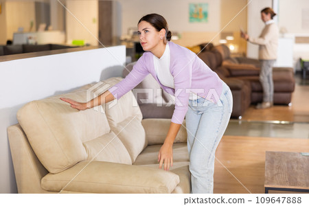 Woman trying out armchair in furniture showroom Woman trying out armchair in furniture showroom 109647888
