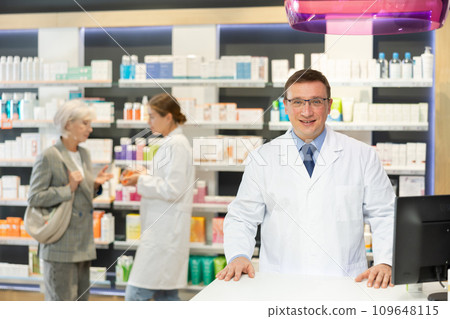 Middle-aged male pharmacist posing in chemist's shop with large assortment Middle-aged male pharmacist posing in chemist's shop with large assortment 109648115