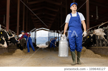 Young boy farmer with can works on dairy farm 109648127