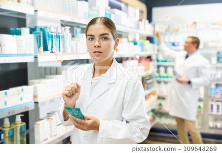Girl pharmacist carefully reads the information on the label of a medicinal intimate hygiene in pharmacy 109648269