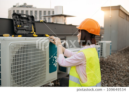 Lady engineer taking screwdriver and fixing cooling system Lady engineer taking screwdriver and fixing cooling system 109649534