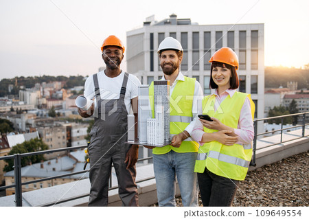 Multicultural designers with equipment posing on rooftop Multicultural designers with equipment posing on rooftop 109649554