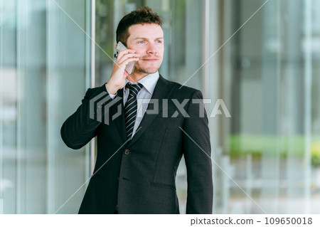 Western businessman calling on smartphone Western businessman calling on smartphone 109650018
