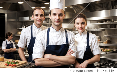 Portrait of chefs team in commercial kitchen. Happy chef working in kitchen at restaurant. smiling confident chefs standing at kitchen in restaurant Portrait of chefs team in commercial kitchen. Happy chef working in kitchen at restaurant. smiling confident chefs standing at kitchen in restaurant 109650116