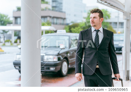 A Western businessman waiting for a bus or taxi at the station to go on a business trip. A Western businessman waiting for a bus or taxi at the station to go on a business trip. 109650965