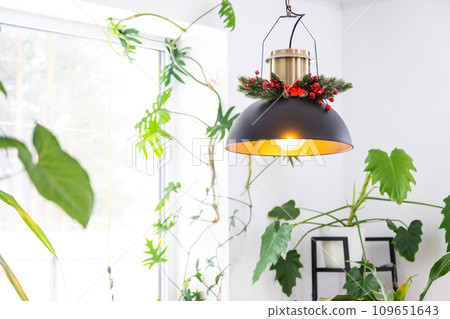 Black retro metal loft style lampshade with Christmas decor  and many indoor plants on a window in a white interior. New Year, comfort at home 109651643
