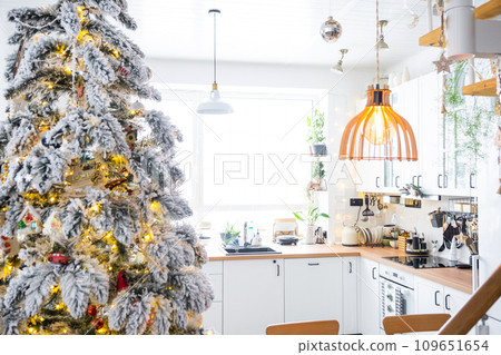 Festive Christmas decor in white kitchen, modern rustic interior with a snowy Christmas tree and fairy lights. New Year, Christmas mood, cozy home. The general plan Festive Christmas decor in white kitchen, modern rustic interior with a snowy Christmas tree and fairy lights. New Year, Christmas mood, cozy home. The general plan 109651654