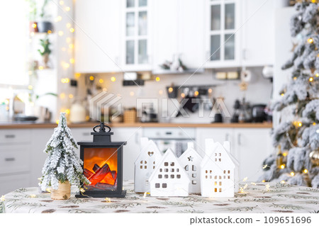 Cozy Christmas decor tiny house of small size on table of festive white modern kitchen. Gift for New Year. Insurance, moving to new house, mortgage, rent and purchase real estate 109651696