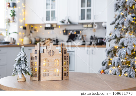 Cozy Christmas decor tiny house of small size on table of festive white modern kitchen. Gift for New Year. Insurance, moving to new house, mortgage, rent and purchase real estate 109651773