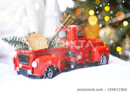 Red retro car with a Christmas tree decorates with the house key in the pickup truck for Christmas. Buying a home, moving, mortgage, loan, real estate, festive mood, New Year Red retro car with a Christmas tree decorates with the house key in the pickup truck for Christmas. Buying a home, moving, mortgage, loan, real estate, festive mood, New Year 109651968