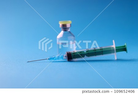 Closeup of medicine jar and syringe on blue background Closeup of medicine jar and syringe on blue background 109652406