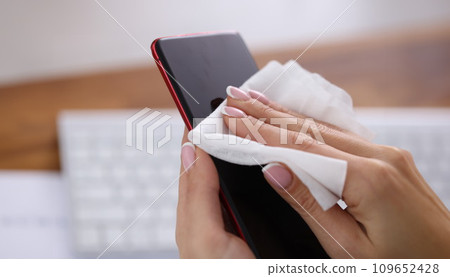 Woman wiping screen of mobile phone with damp cloth closeup Woman wiping screen of mobile phone with damp cloth closeup 109652428