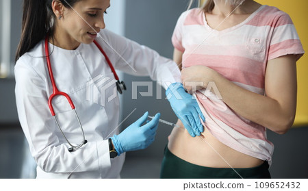 Doctor making injection of insulin into abdomen of female patient Doctor making injection of insulin into abdomen of female patient 109652432